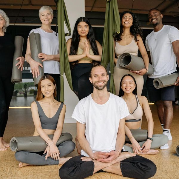 Group of diverse people smiling and preparing for a yoga class.